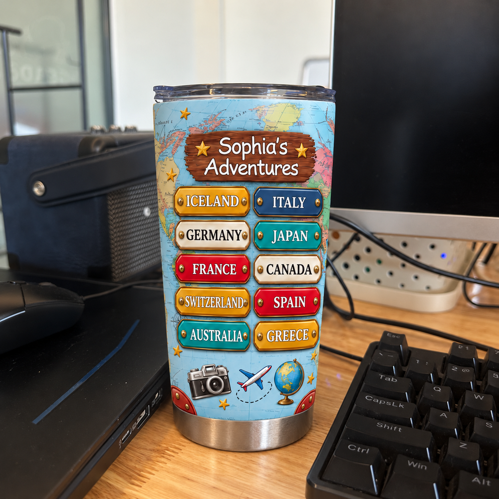 Personalized travel map tumbler featuring world map background standing on a wooden desk near a keyboard.