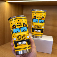 A hand holding a personalized stainless steel school bus tumbler with DAVID on the front and a #1 license plate.