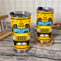 Two yellow school bus driver tumblers in stainless steel with custom name displayed side-by-side on a rustic wooden surface.