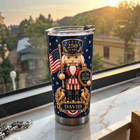 Insulated travel tumbler with patriotic nutcracker soldier on windowsill at sunset overlooking town buildings.