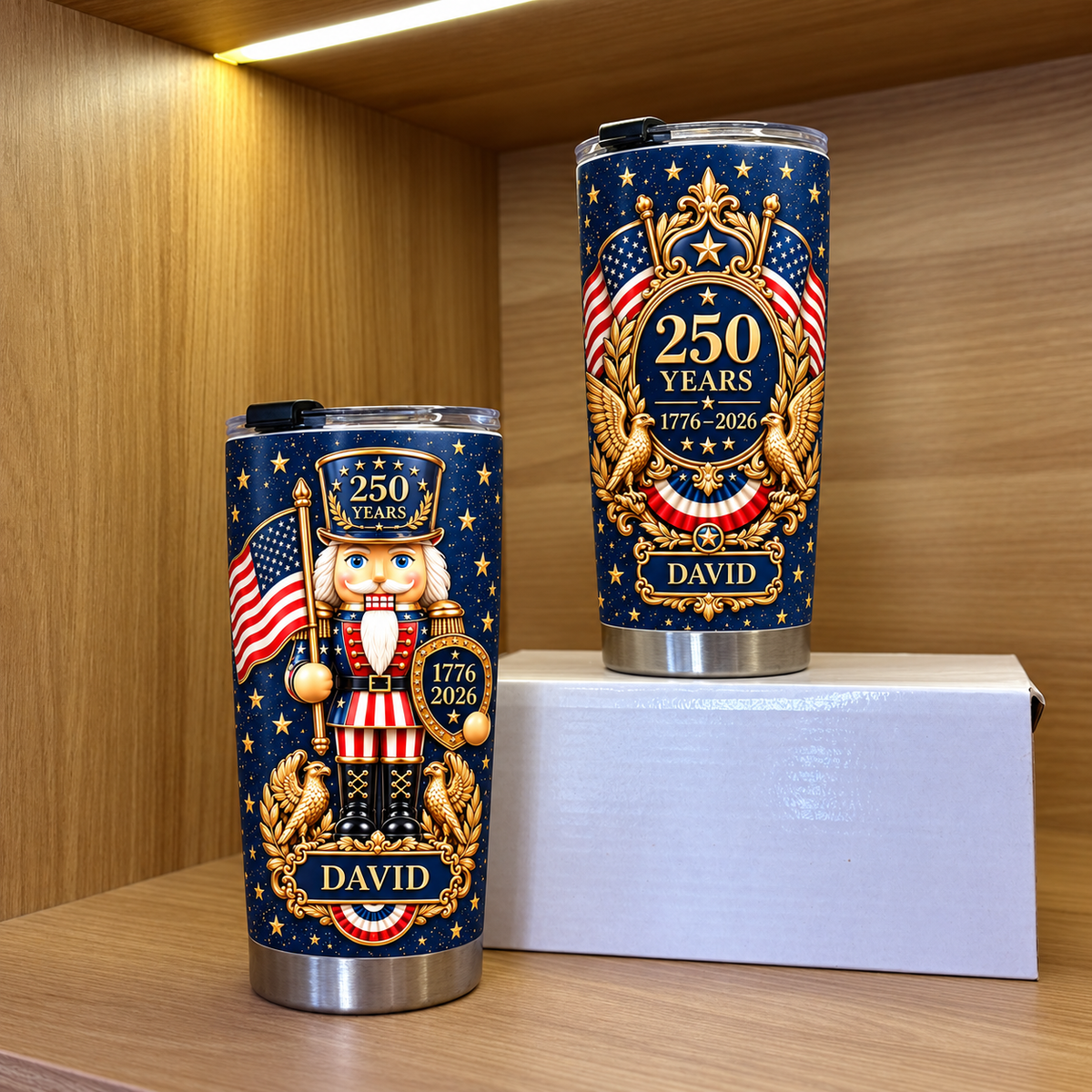 Two custom name patriotic tumblers displayed upright on a wooden shelf inside a display cabinet.