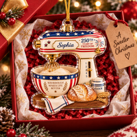 Bread lover gift ornament shaped like a patriotic mixer shown inside a red gift box lined with red shredded paper.