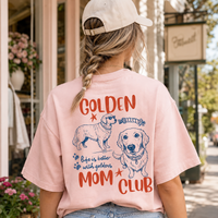 Woman from back in light pink graphic t-shirt with braided hair, standing outside flower shop.