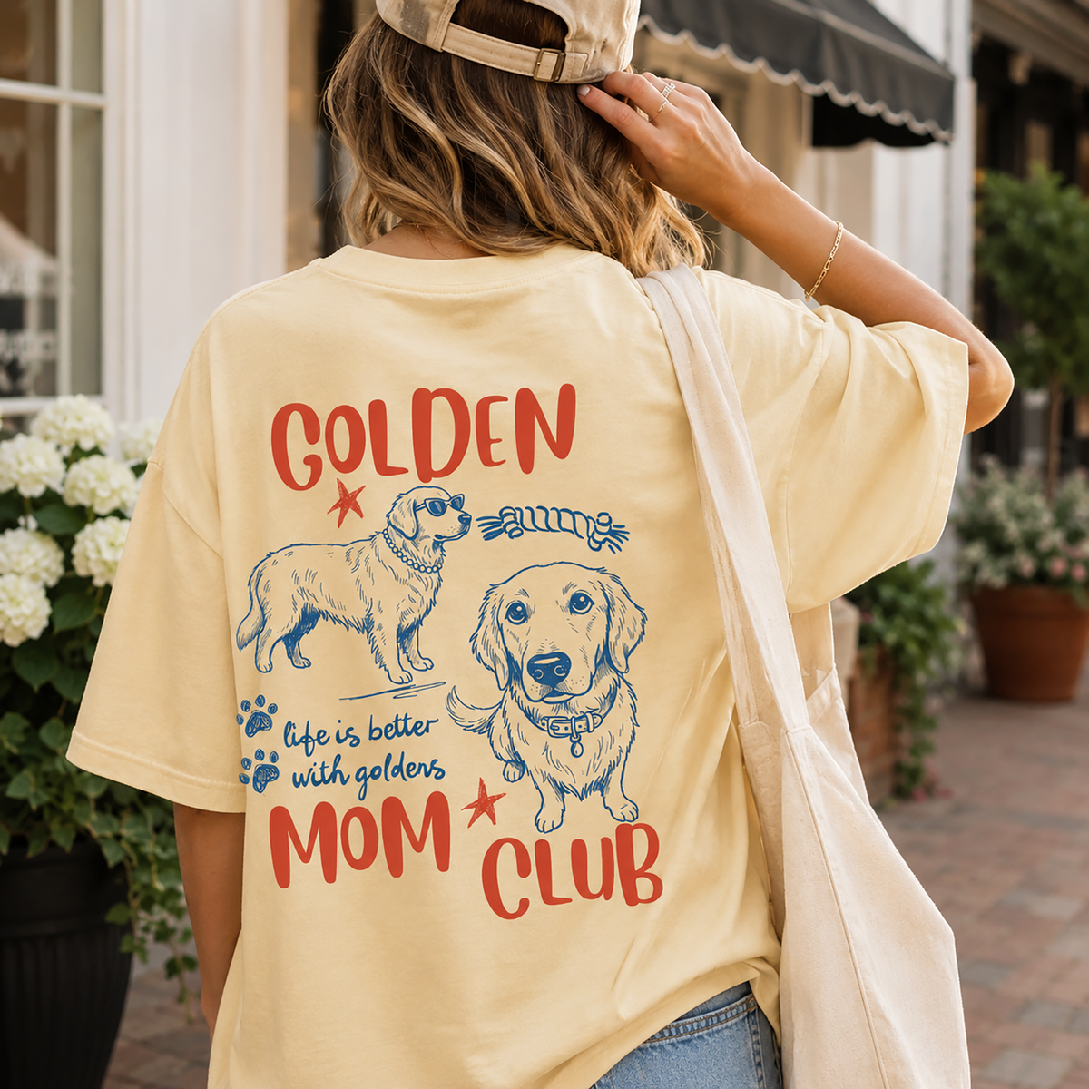 Woman wearing yellow washed t-shirt with golden retriever design and canvas tote bag outdoors.