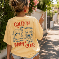 Woman wearing yellow vintage tee with dog mom graphic, flashing peace sign on sunny sidewalk.