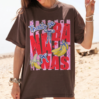 Dark brown t-shirt featuring coquette bow and banana graphic on a sandy beach background.