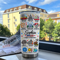 Insulated stainless steel tumbler upright on a ledge overlooking a sunny building.