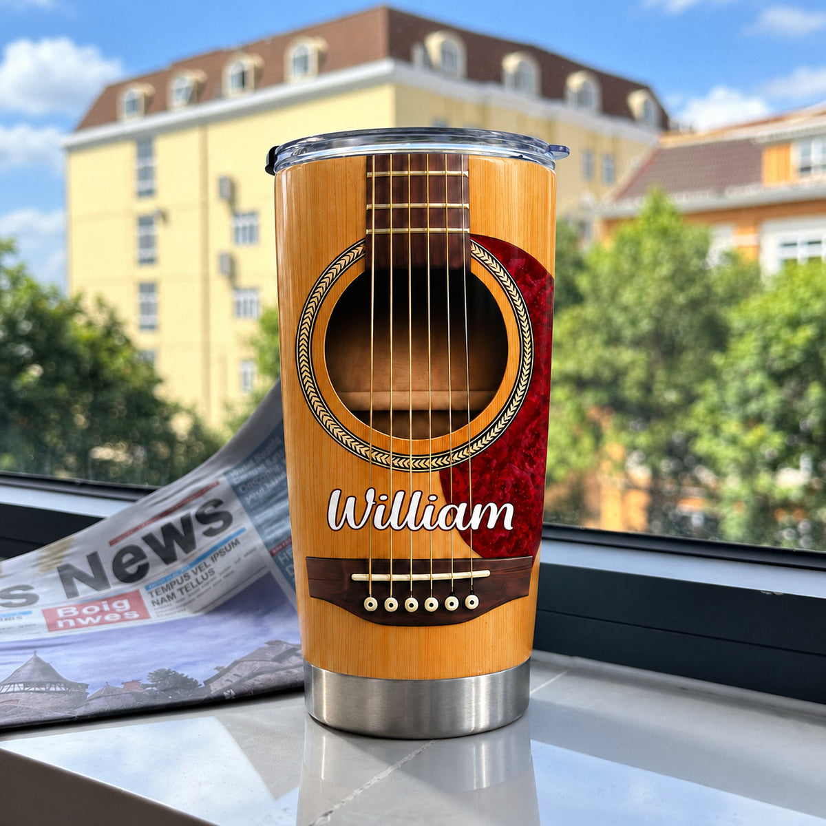 Acoustic Guitar Tumbler Personalized with a custom name displayed on a windowsill with a blurred city building background.