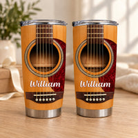 Two personalized acoustic guitar tumblers with wood grain print and the name William standing on a wooden surface.