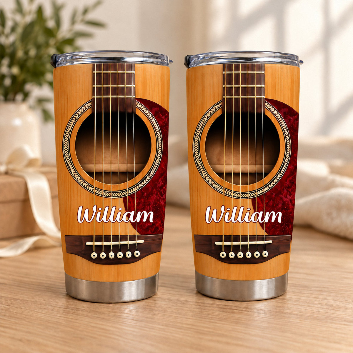 Two personalized acoustic guitar tumblers with wood grain print and the name William standing on a wooden surface.