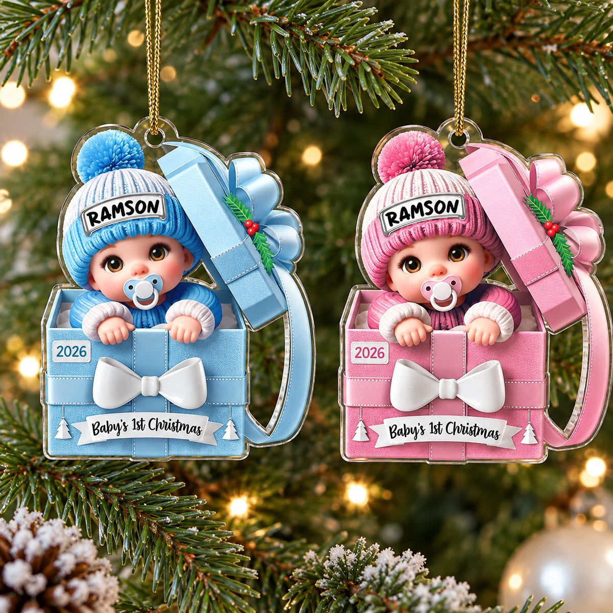 Blue and pink baby's first holiday keepsake ornaments hanging on illuminated Christmas tree branches.