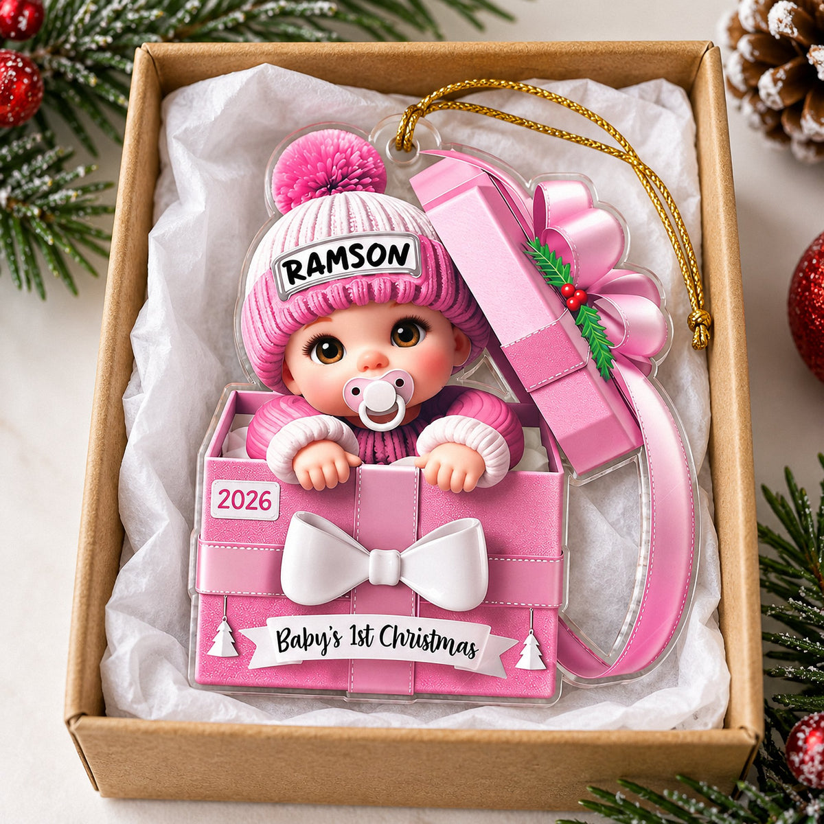 Baby's 1st Christmas ornament in pink gift box shape inside a cardboard gift box with tissue paper.