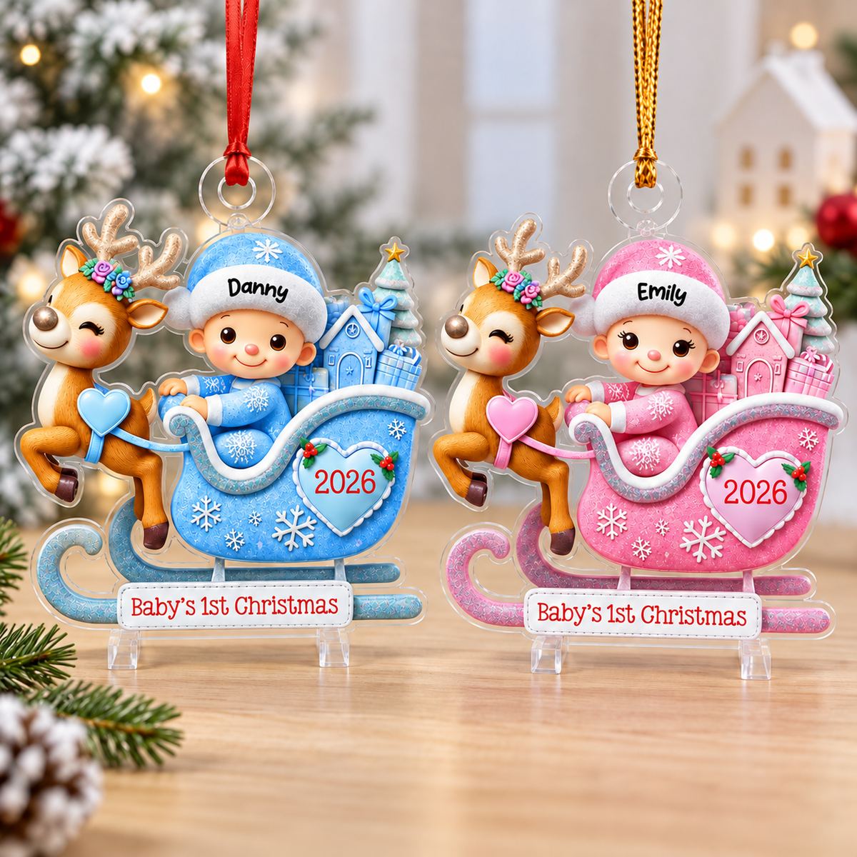 Two custom acrylic Christmas ornaments in blue and pink display cartoon babies in reindeer sleighs.