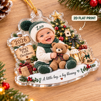 Close-up of the baby boy personalized acrylic ornament resting on a wooden surface with a 2D flat print label.