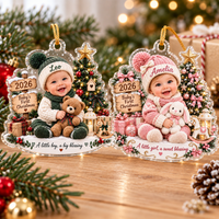 Two Baby's First Christmas Ornament Personalized designs, boy in green and girl in pink, displayed on wood.
