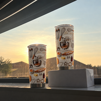 Two cream custom name tumblers with embossed mixer and rolling pin graphic on a windowsill at sunset.
