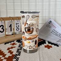 Insulated baking-themed tumbler with 3D embossed mixer design standing next to a calendar and newspaper.