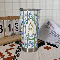 A personalized mahjong tumbler stands next to a wooden calendar block and a rolled newspaper.