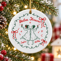 A single round ceramic Christmas ornament hanging on a pine tree with Besties Forever text, green wreath, and custom names