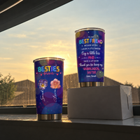 Two custom name insulated tumblers on a windowsill at sunset with soft warm light glowing behind buildings