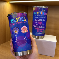 Hand holding custom name insulated tumbler with purple galaxy bokeh and floral design on wooden shelf with another tumbler on