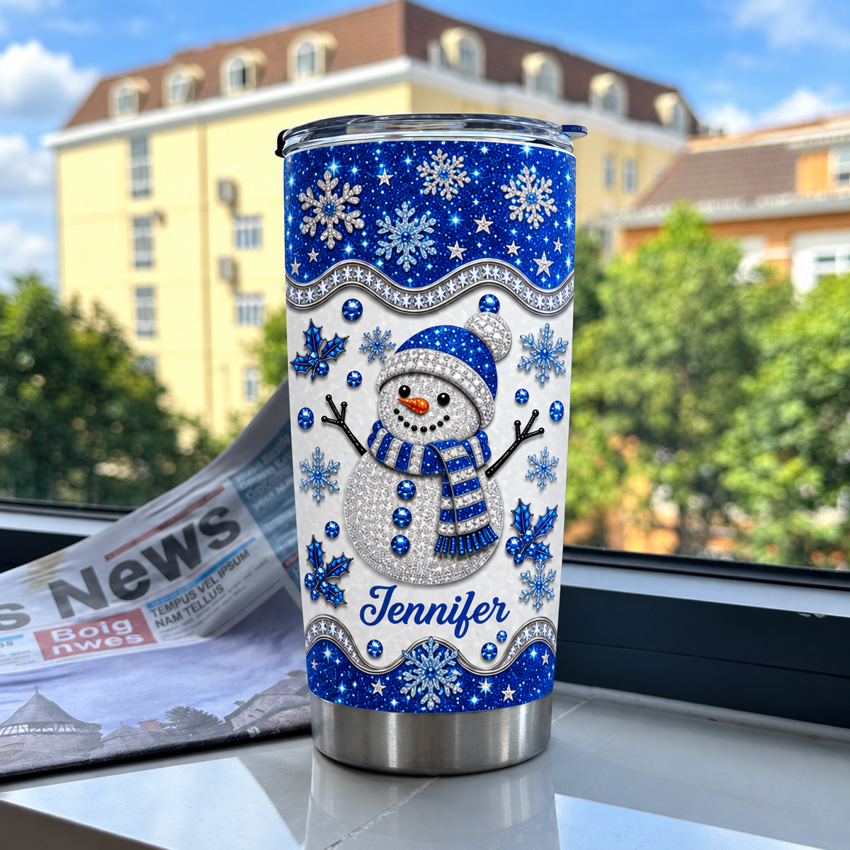 Blue glitter snowman tumbler on a marble windowsill with newspaper backdrop.