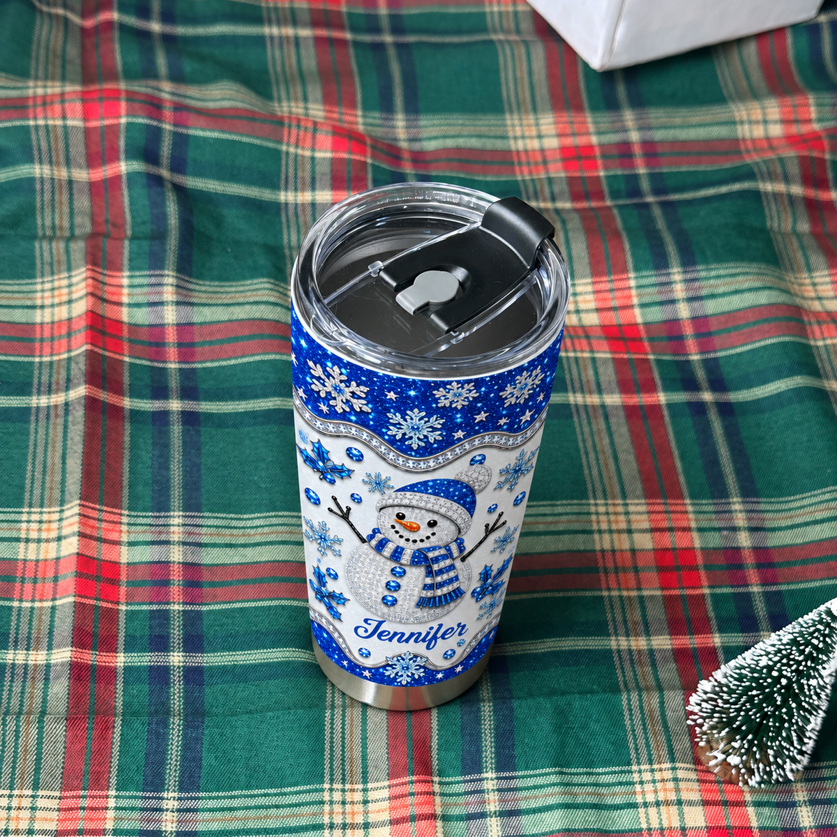 Blue glitter snowman tumbler on green plaid blanket with mini tree.