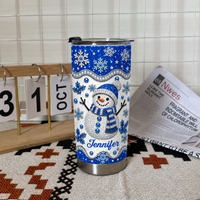 Blue glitter snowman tumbler next to calendar showing October and newspaper.