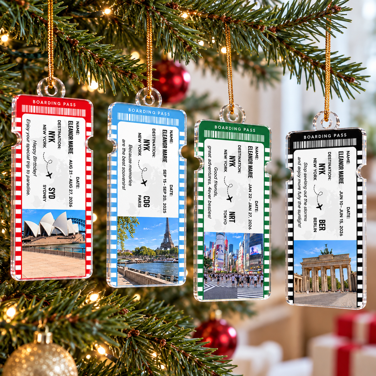 Four personalized travel gift ornaments in red, blue, green, and black hanging on a lit Christmas tree.