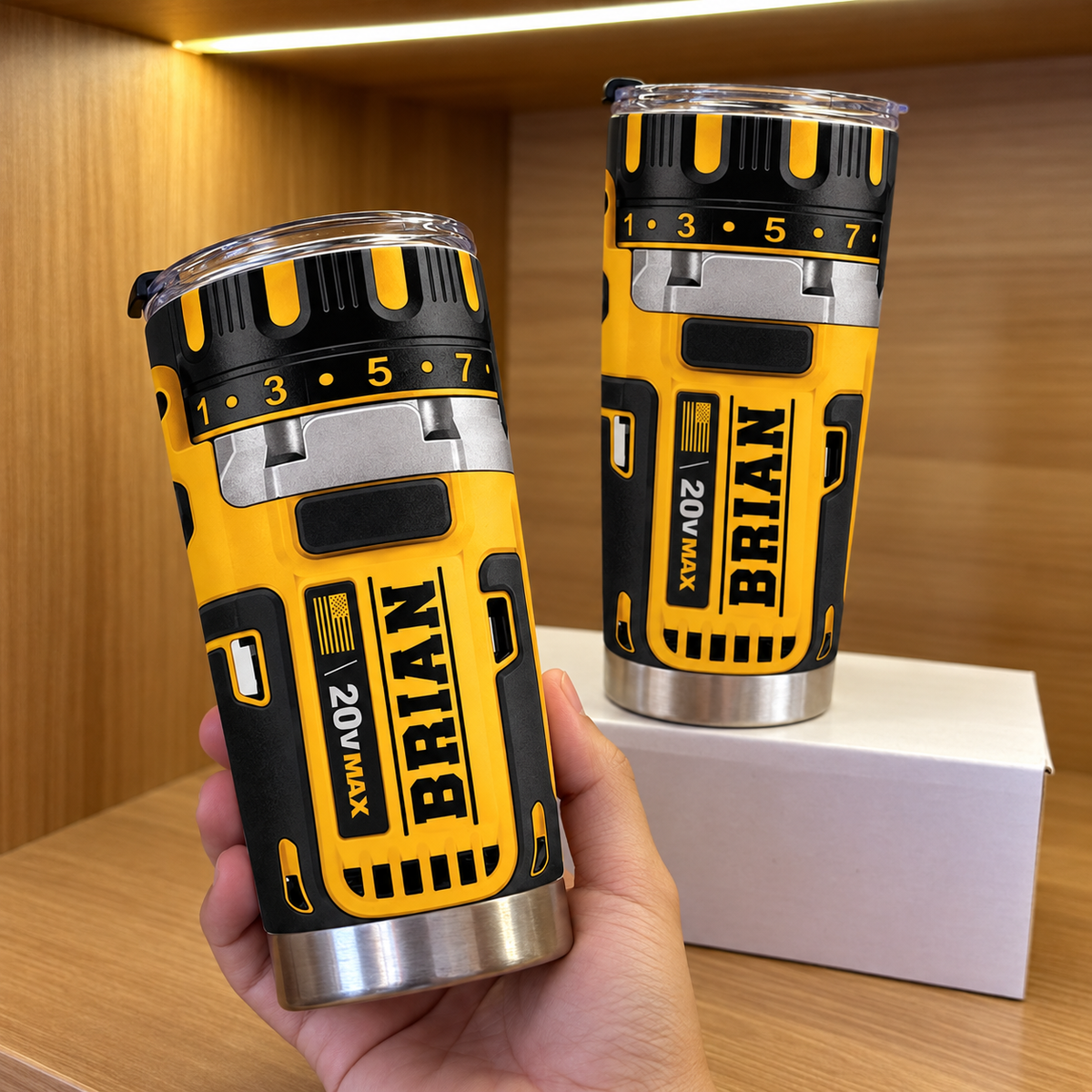 Hand holding drill theme stainless steel insulated cup featuring yellow and black graphic and name BRIAN, with another on