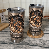 Two custom cowboy tumblers with a bucking bull design standing on a textured surface next to a wooden desk calendar.