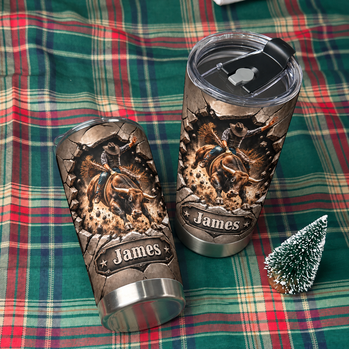 Two custom name rodeo tumblers laid out on a green plaid blanket next to a small decorative miniature pine tree.