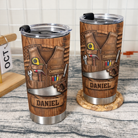Two stainless steel tumblers with carpenter tool vest graphics and custom name panels on a rustic table.