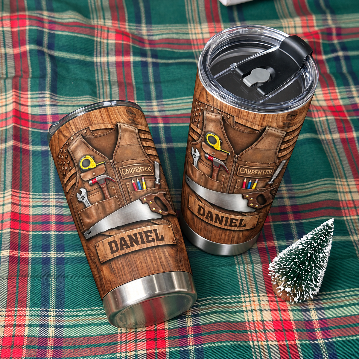 Two custom woodworker tumblers displayed on a green plaid fabric next to a small faux Christmas tree.