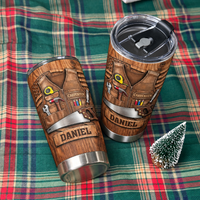 Two custom woodworker tumblers displayed on a green plaid fabric next to a small faux Christmas tree.