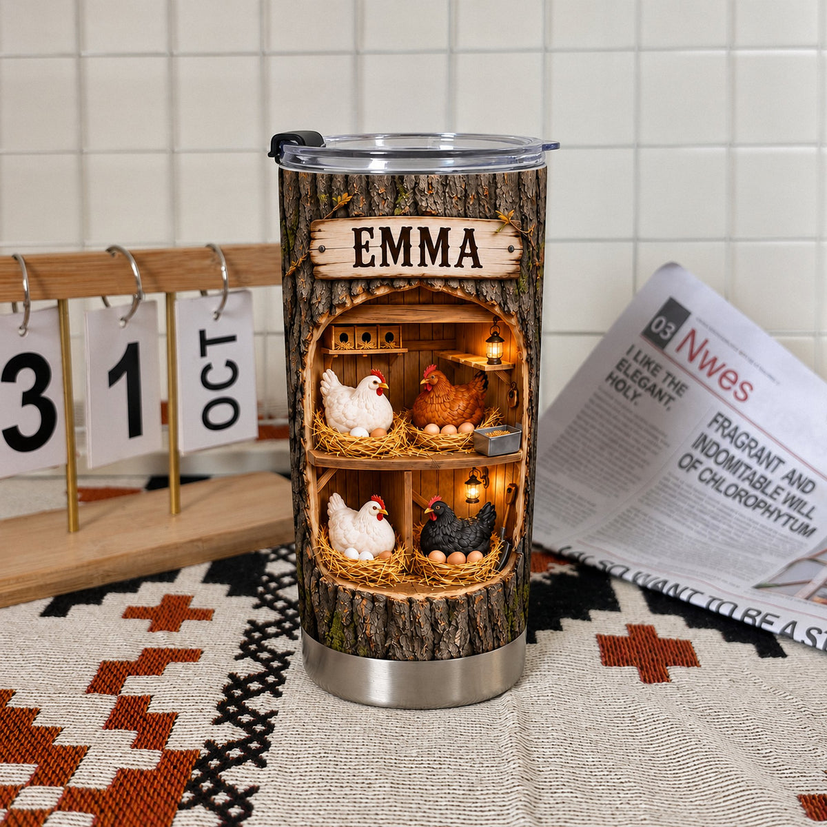 Custom name tumbler with chicken coop design resting on a patterned cloth near a desk calendar.