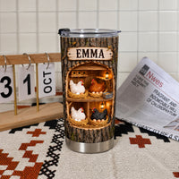 Custom name tumbler with chicken coop design resting on a patterned cloth near a desk calendar.