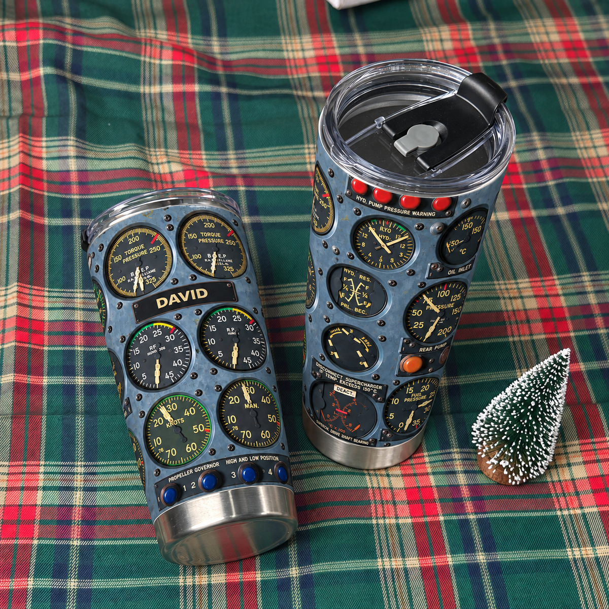 Two cockpit instrument panel tumblers displayed on a green and red plaid fabric next to a mini tree.