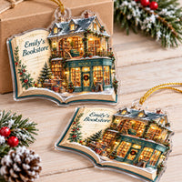 Two personalized acrylic bookstore Christmas ornaments on a wooden tabletop near pine branches.