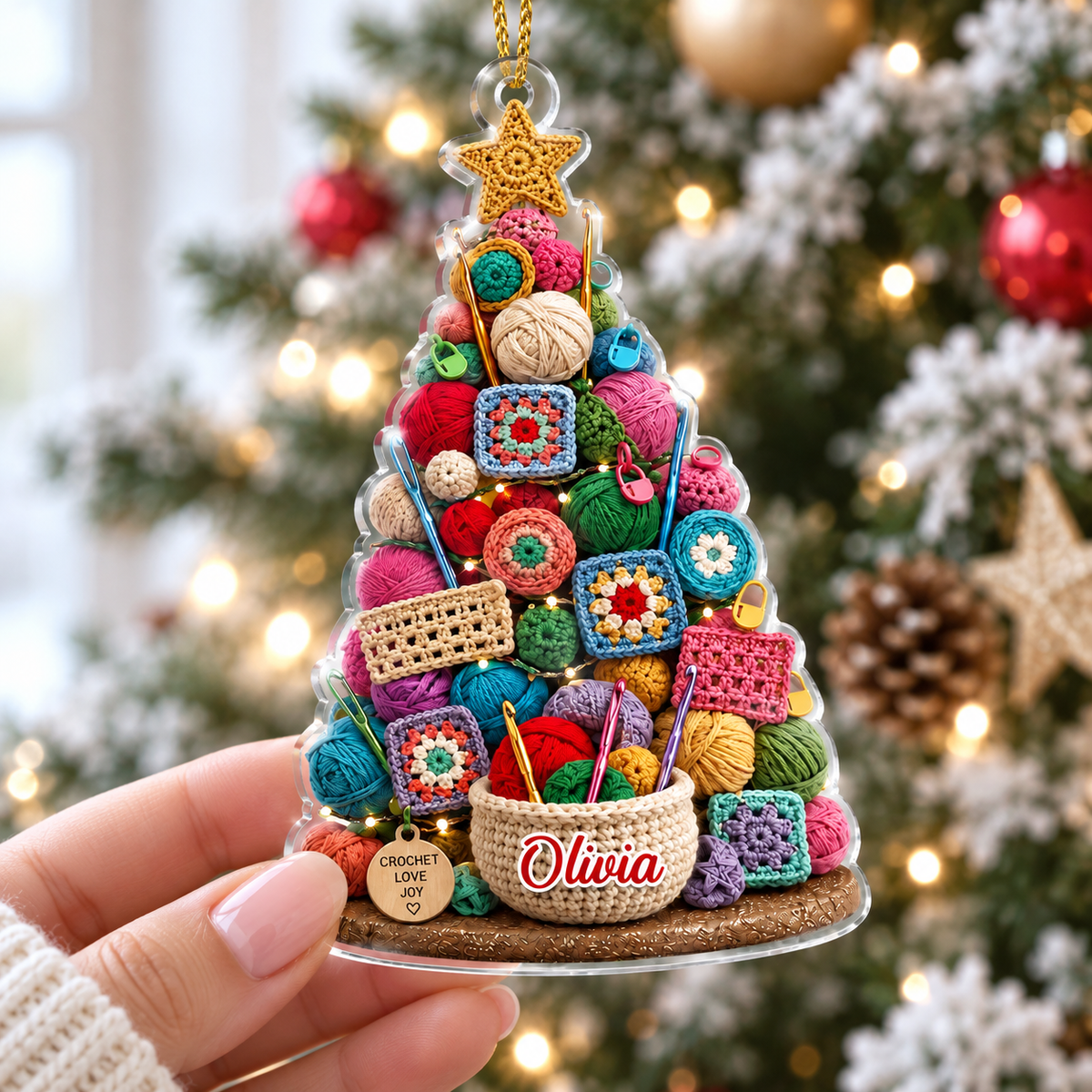 Hand holding a personalized acrylic Christmas tree ornament with a colorful yarn and granny square design against a holiday