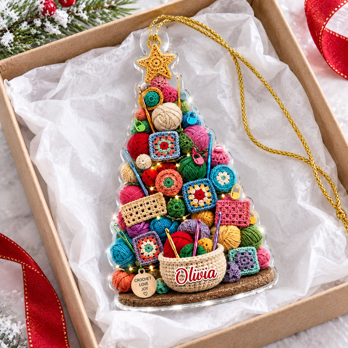 Personalized acrylic Christmas tree ornament lying inside a gift box lined with white tissue paper and red ribbon.