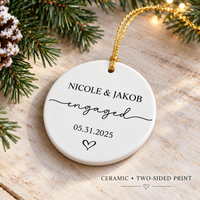 Round white ceramic ornament featuring custom text and a gold hanging loop on a rustic wooden surface with pinecones.