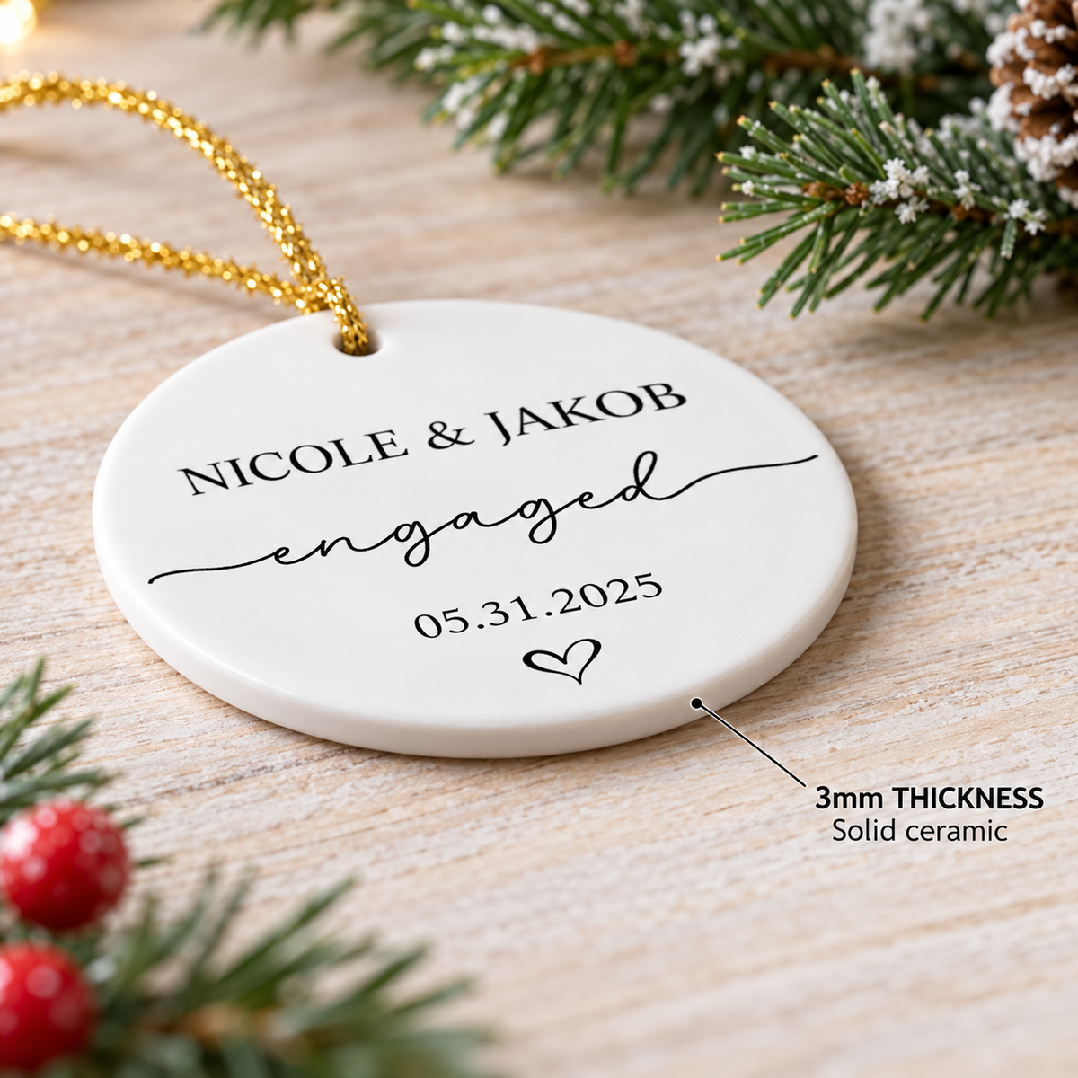 Close-up of a 3mm thick round ceramic ornament displaying custom couple names and engagement date on wooden surface.
