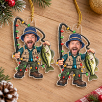 Two custom photo fisherman ornaments laid flat on a wooden surface with pine branches.