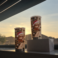 Two Christmas highland cow leopard print tumblers with name Sophia on windowsill and box at sunset with warm glow.