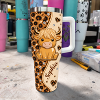 A 40oz custom name tumbler with a brown leopard print design and a cute baby highland cow on a workshop table.
