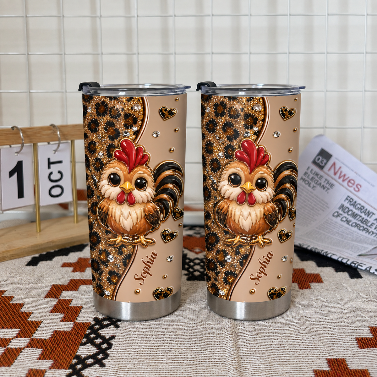 Two personalized chicken cups with leopard print and cute roosters on a woven mat with a newspaper and calendar.