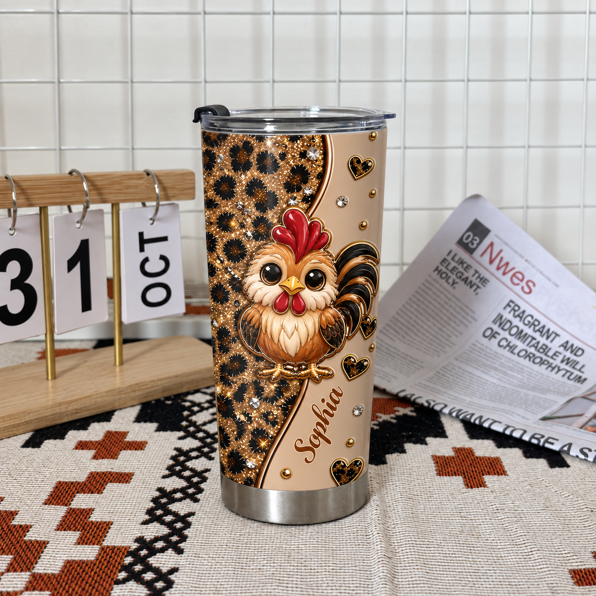 A personalized chicken cup with a cute rooster and leopard print on a woven mat next to a small wooden calendar.