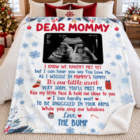 Folded white Sherpa fleece pregnancy announcement blanket displayed neatly on a white bed with pillows.