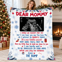 Expecting mother holding a white baby shower keepsake blanket with red and blue lettering.